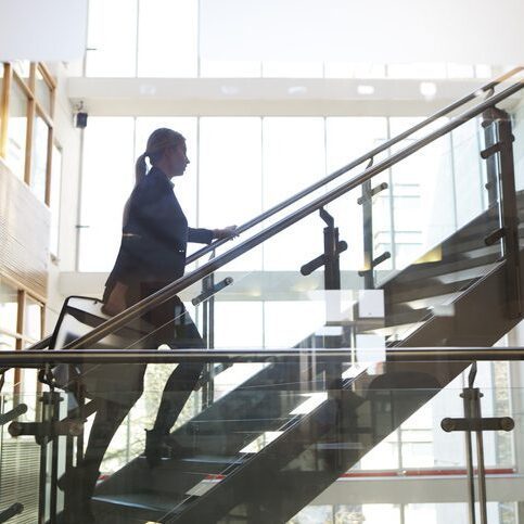 Woman walking up stairs in office building 